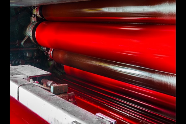 close-up of printing press with red ink rollers in operation