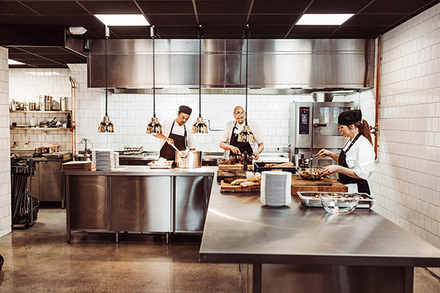 chefs working in a commercial kitchen with stainless steel equipment