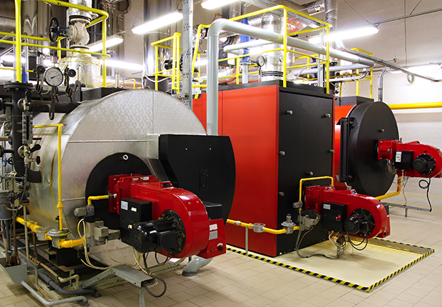 industrial boiler room with two large boilers, pipes, valves, and yellow safety railings