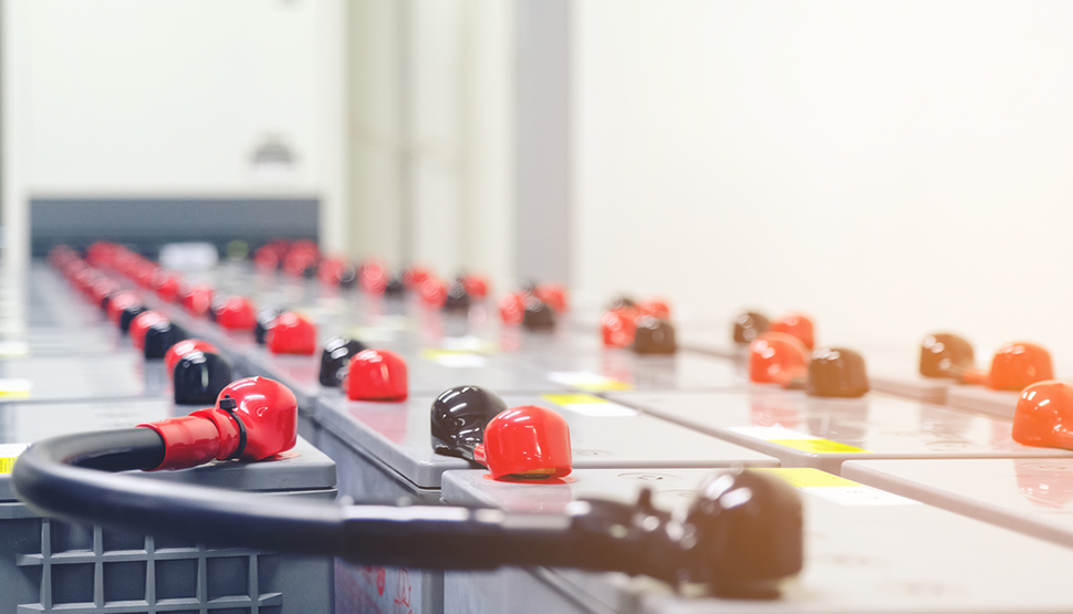 industrial battery bank with rows of energy storage batteries featuring red and black terminal caps in a data center or backup power system